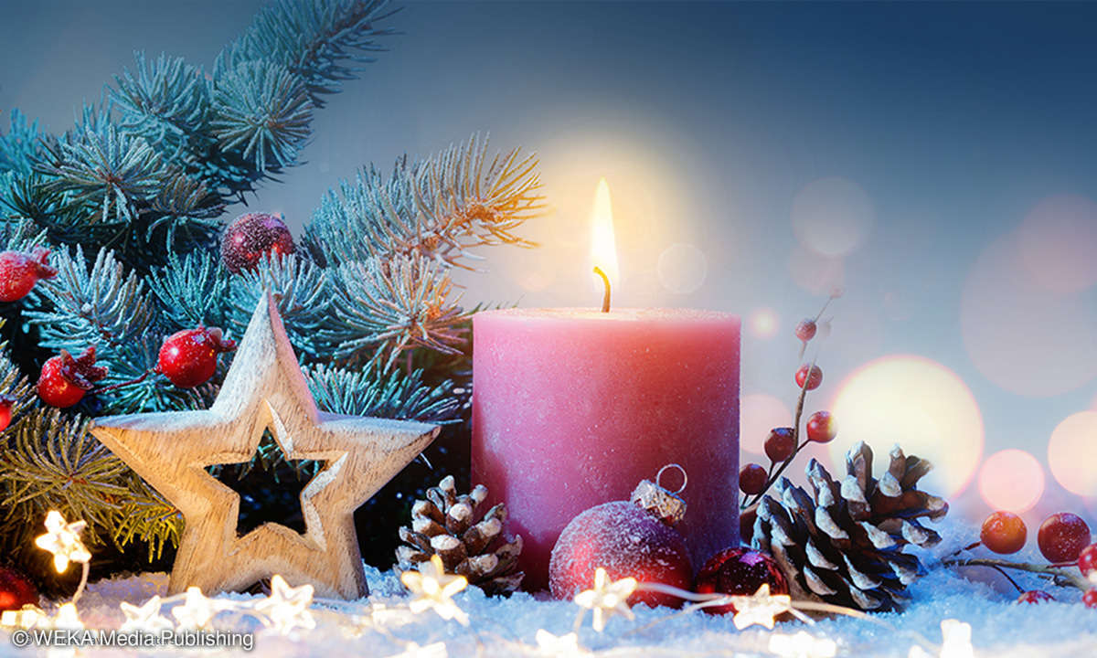 Adventskerze vor weihnachtlicher Dekoration